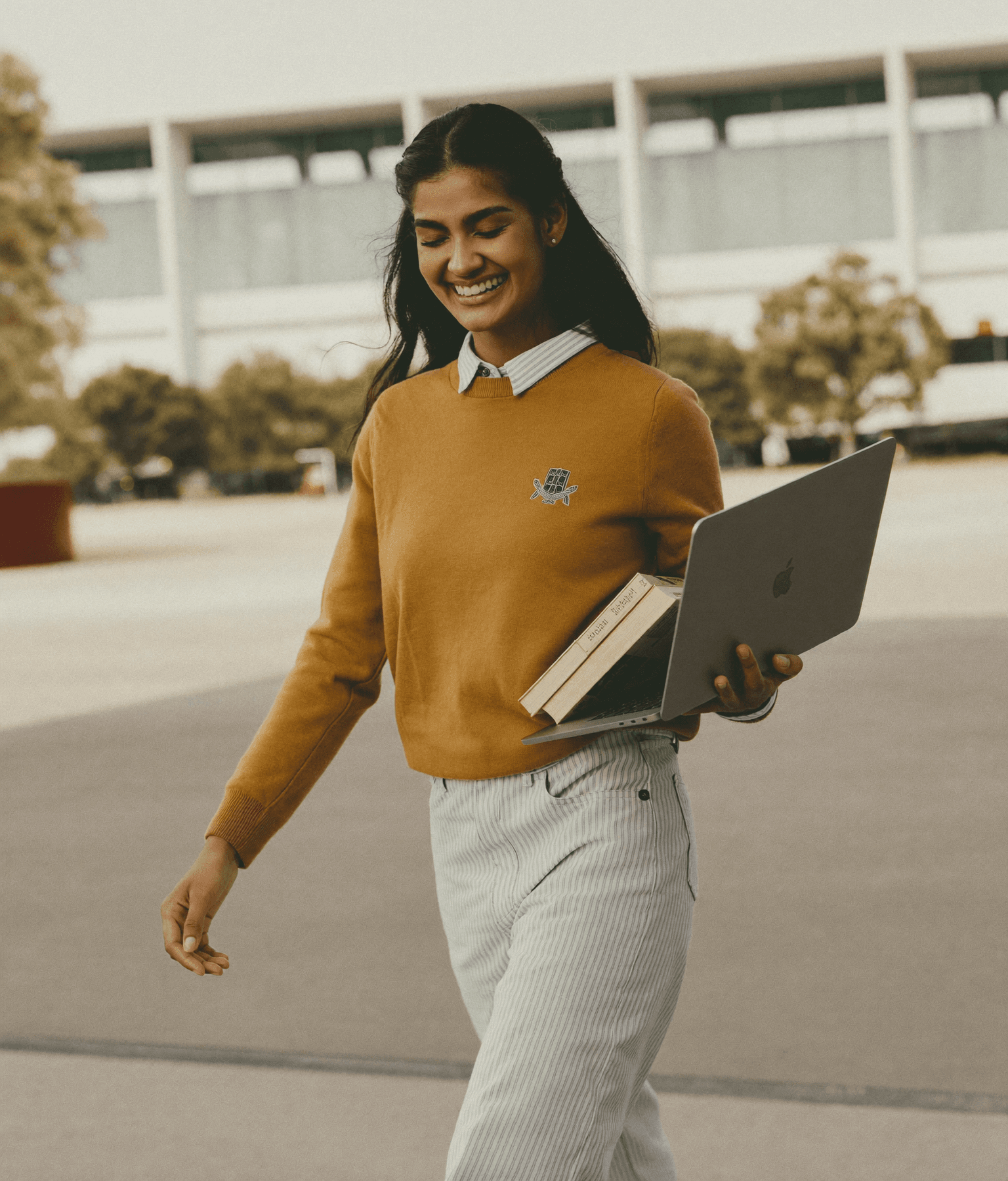 Smiling Indian student walking across a university campus